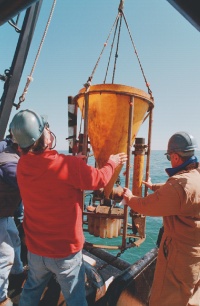 sediment trap hanging over the deck being steadied by two men