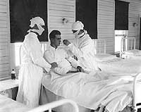 Photo # NH 60309:  Masked medical personnel treating an influenza patient at New Orleans Naval Hospital, circa autumn 1918