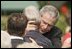 President George W. Bush embraces one of the hundreds of family and friends who gathered on the South Lawn of the White House, Friday, Sept. 9, 2005, during the 9/11 Heroes Medal of Valor Award Ceremony, in honor of the courage and commitment of emergency services personnel who died on Sept. 11, 2001. 