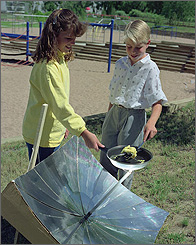 Photo of students cooking an egg using a solar collector.