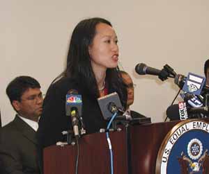 Kam Wong, EEOC Trial Attorney in the New York District Office, stands at the podium to announce a litigation filing against the landmark Plaza Hotel in Manhattan, as several charging parties look on (seated on the right). 