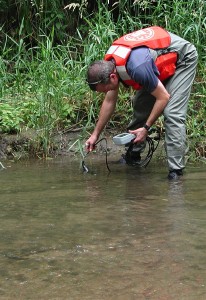 USGS scientist measuring pH and other water properties on the banks of Fourmile Creek, Iowa, before collecting a sediment sample for laboratory biodegradation experiments.