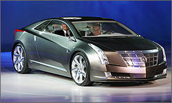 Photo of a driver and passenger in two-door coupe, which is parked on an autoshow display turntable.