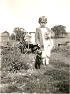 Antique photo of a small boy and a kitten outdoors