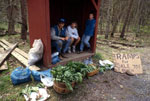 Three young people sitting inside a wooden shelter with ramps displayed for sale outside.