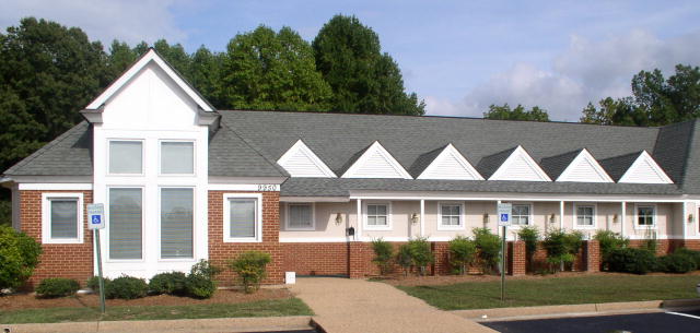 Picture of a one story brick and white building with handicap parking in front.