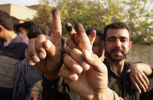 Photo shows a group of Iraqi men.  Four are displaying their ink-stained fingers.