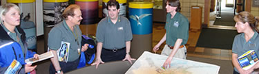 A photo of a visitor use assistants giving an orientation by the map of Alaska