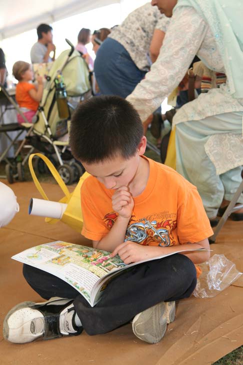 A boy sitting cross-legged on the floor, reading a book.