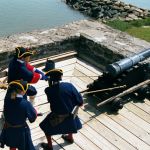 Volunteer re-enactors struggle to pull an iron cannon away from the rampart walls.
