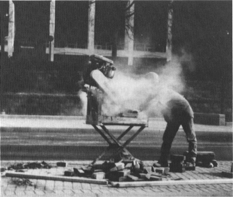 image of a construction worker sawing masonry without dust control or a respirator