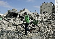 A Palestinian youth pushes a bicycle past the rubble of a house after it was hit in an Israeli missile strike in Gaza City, Monday, 12 Jan. 2009