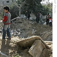 Palestinians gather around a crater caused by an Israeli strike, at the damaged Sheik Radwan cemetery, following Israeli military operations in Gaza City, 14 Jan 2009