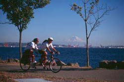 Photo of Two Bicyclists with scenic lake and mountain background