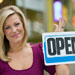 Woman standing next to Open for business sign