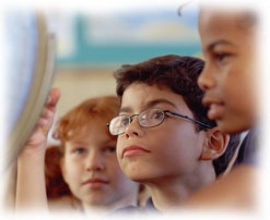 Photograph of three children looking at a globe in a classroom.