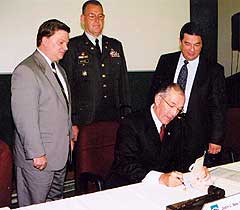 Chairman Nau signs program comment as three Army personnel look on