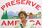Mrs. Bush stands in front of the Preserve America logo