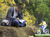 Student studying on a rock on central campus.