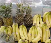 Photograph of pineapples and bananas ready for sale at a grocery store.