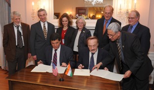 Dr. Zerhouni and Dr. Bhan from India, sign an Indo-U.S. agreement at a Stone House ceremony. Seven staff members stand on the side and behind them, including Fogarty director Dr. Roger Glass.