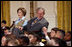 President George W. Bush, sitting with Mrs. Laura Bush, reaches to hold the hand of a young child Monday, Dec. 8, 2008 in the East Room of the White House, during the Children's Hoilday Reception and Performance.