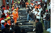 Rescue workers stand among bags of victims of a landslide at a cemetery in Alta Verapaz, 05 Jan 2009