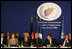 Mrs. Laura Bush offers remarks at the U.S.-Afghan Donor's Conference as visuals of one of her trips play on monitors in the center of the room for representatives from around the world to view. Seated next to her, from left, are Afghan Foreign Minister Dr. Ragin Dadfar Spanta, Afghan President Hamid Karzai, and French President Nicholas Sarkozy. The June 12, 2008 Paris meeting was at the Center de Conferences Internationals.