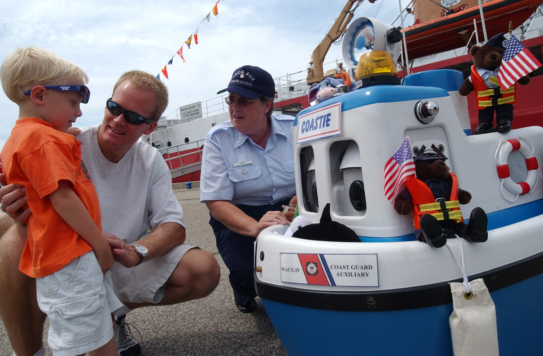 Father and son talk with a Coast Guard Auxiliarist and "Coastie" the safety boat