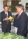 Secretary Leavitt and Senator George Voinovichtests snapping an ear of corn in half inside a walk-in produce cooler. HHS photo by Keith Nahigian
