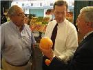 Secretary Leavitt and Commissioner von Eschenbach holding oranges at a produce stand. HHS Photo by Holly Babin