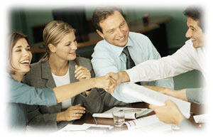 Group of people shaking hands and laughing at a meeting table.