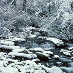 Snow blankets the rocks in a river in the park.