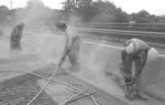 Trabajador en una nube densa de polvo en un sitio de construcción en una vía