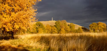 Sunset casts a golden glow over the grounds, the monument can be seen atop the hill in the distance