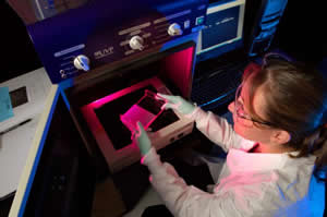 A laboratorian places a PFE gel under UV light.