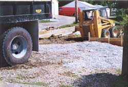 Photo 2 – View from sidewalk showing gravel pile and rear of skid-steer loader. 
