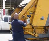 An operator at the controls of the trash truck operating the packer panel.