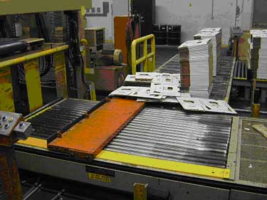 Exhibit #2. A picture of the automated roller conveyor system that brings the boxes to the table that feeds the boxes into the waxing system.