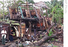 A Myanmar family stands in front of their house damaged from Cyclone Nargis on the outskirts of Yangon, Myanmar, on Wednesday May 14, 2008.AP