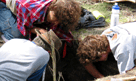 Three people lying on the ground searching for artifacts. 