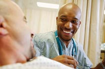 Male nurse talking to patient in hospital bed