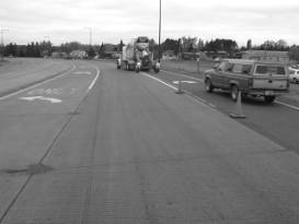  Figure 3-21:  Photographs.  Typical distress manifestations observed at MN-065-064.  This figure is comprised of two photographs labeled A and B.  Photograph A shows transverse cracking parallel to the joint along with staining and spalling.  Photograph B shows the three lanes of traffic in the project site area and no distress is visible.  