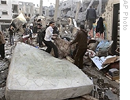 Palestinians collect their belongings from a damaged building after an Israeli airstrike in Gaza City, 14 Jan 2009