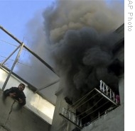 A Palestinian man calls for help as smoke rises from a window following an explosion caused by Israeli military operations in Gaza city, 14 Jan 2009