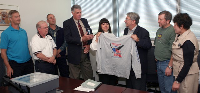 Laboratory Director Mike Anastasio, center, looks at an official Laboratory veterans fun run/walk long-sleeve T-shirt during a presentation Wednesday in the Director's Conference Room at the National Security Sciences Building. Juanita Romero of Applied Engineering Technology is holding the T-shirt with Anastasio. The fun run and walk is November 8 as part of the Lab's observance of Veterans Day.