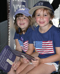 Sisters Shannon and Carlie McLaughlin wait in their grandfather's wheelchair while he tells his story. Their grandfather's name is Charles Joseph Szostak.