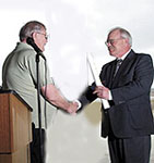 From left, director of the American Foundation for Wildlife of Bismarck, presents Roger Ristevedt, assistant director of the North Dakota Game and Fish Department with the deed for 1,500 acres of land along the confluence of the Missouri and Yellowstone Rivers during dedication ceremonies at the Missouri-Yellowstone Confluence Visitor Center, at the Fort Buford State Historic Site. The transaction ensures the property will remain open to the public for hunting and fishing. Image by Pete Ressler, Williston Herald