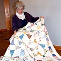 Teresa McGuigan Hentosz with hand-pieced quilt "Sparkling Gems," made in 1998 from old feed bags