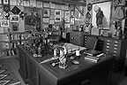 Desk and walls covered with objects of various kinds.